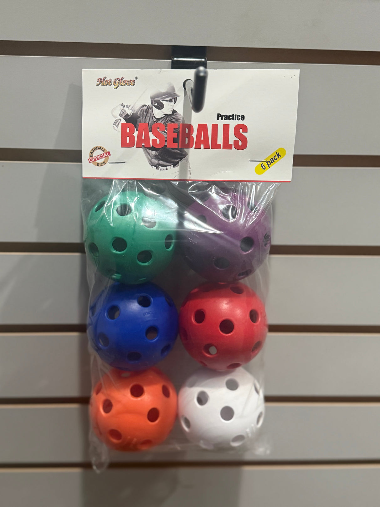 Pack of colorful practice baseballs on a gray slat wall